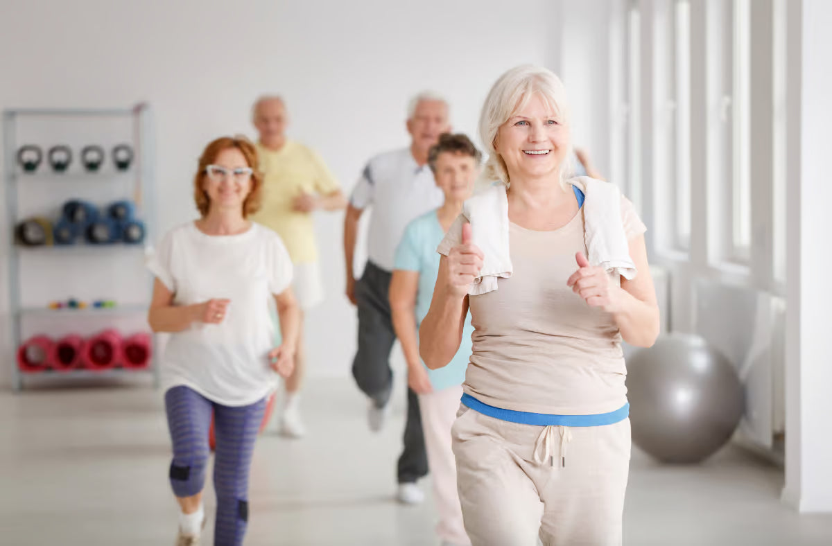 Smiling elderly woman exercising at the gym with other seniors