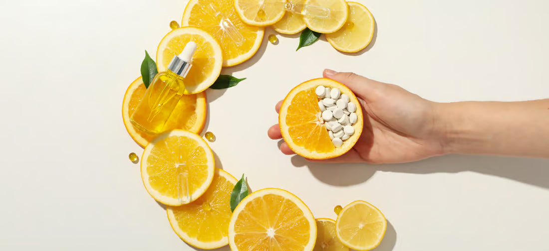 A lemon and an orange arranged in the shape of the letter ‘c’ and an outstretched hand with half of the lemon tablets.