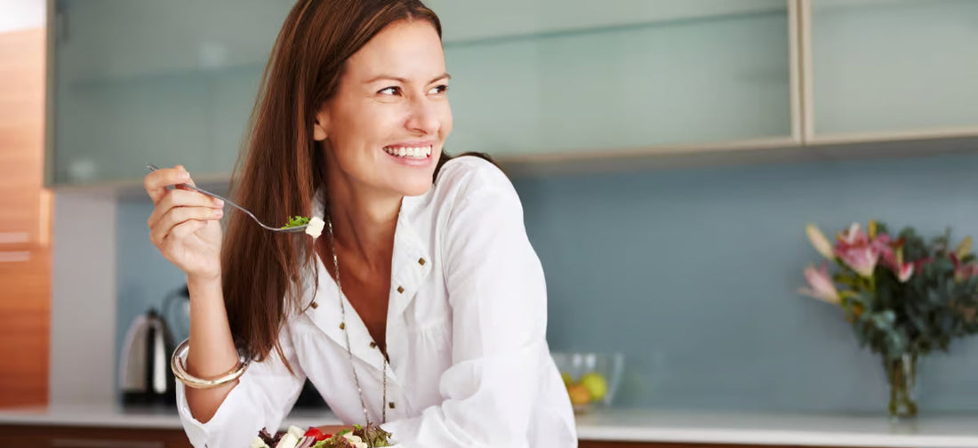 A smiling woman eating a healthy salad.