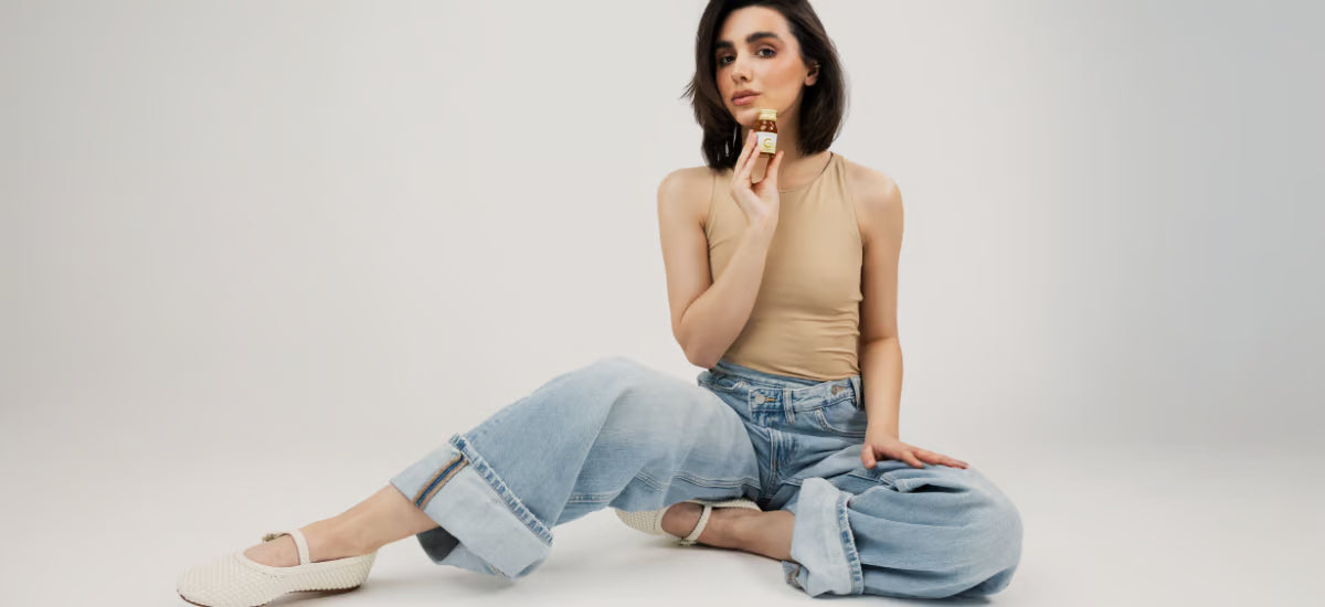 woman with radiant skin and thick hair holding a bottle of Primabiotic Collagen