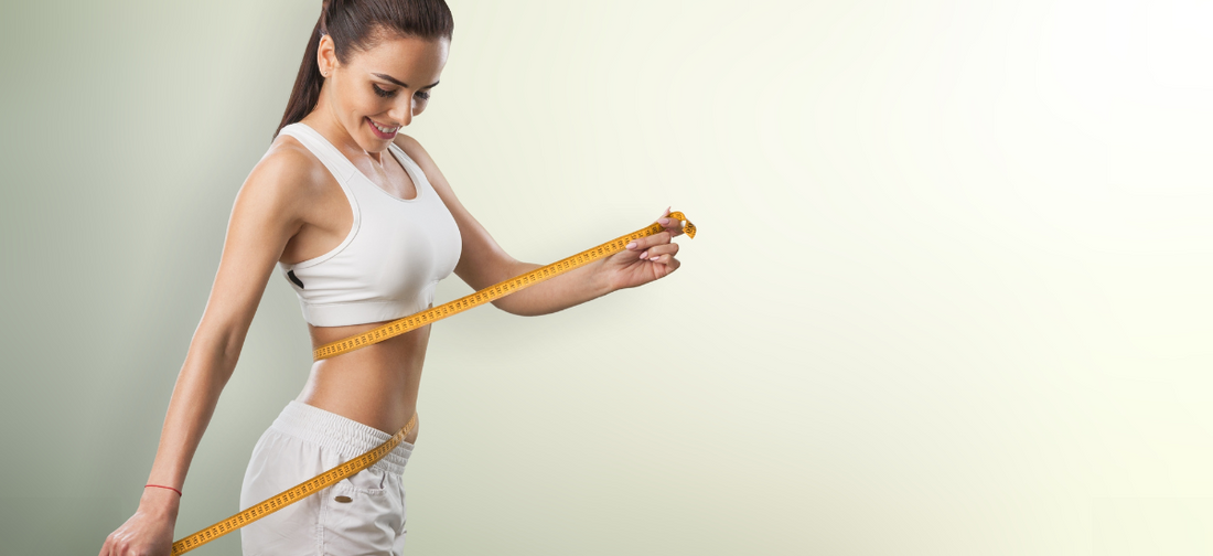 Fit woman measuring her waist with a tape