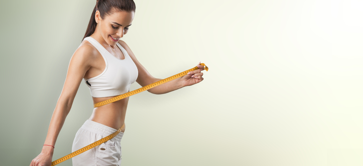 Fit woman measuring her waist with a tape