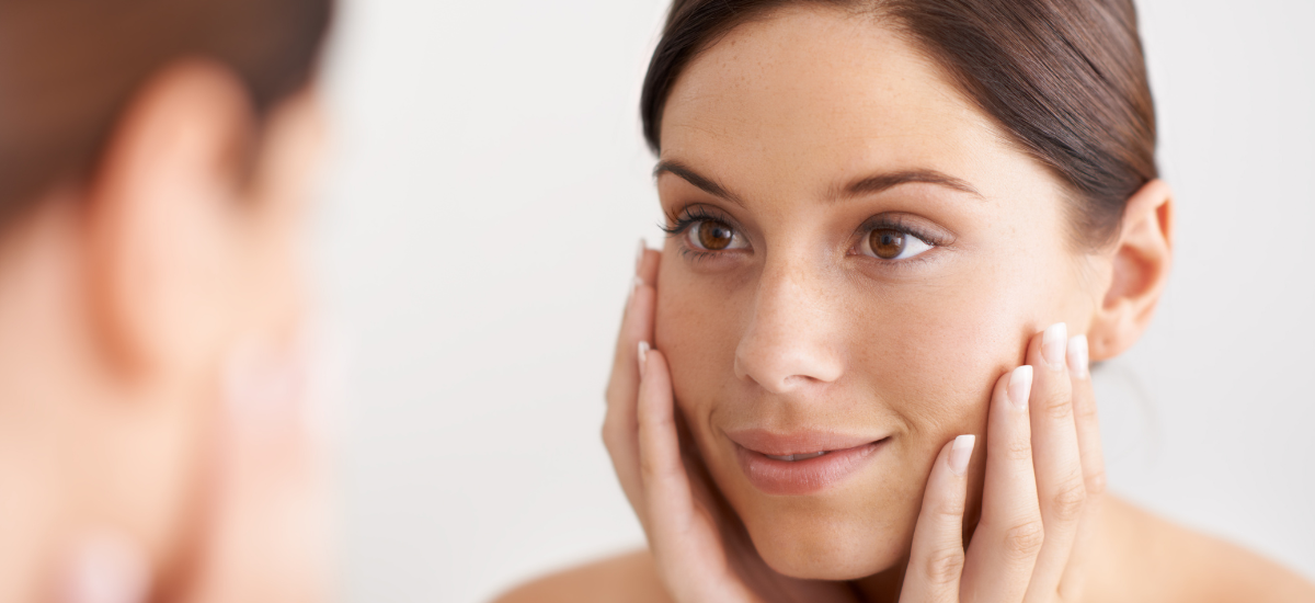 Woman touching her smooth face in the mirror after using Primabiotic Collagen