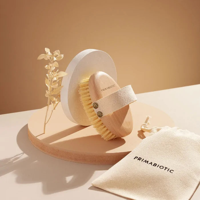 Primabiotic natural body brush with firm bristles and cotton strap, designed for dry brushing and improving skin circulation.