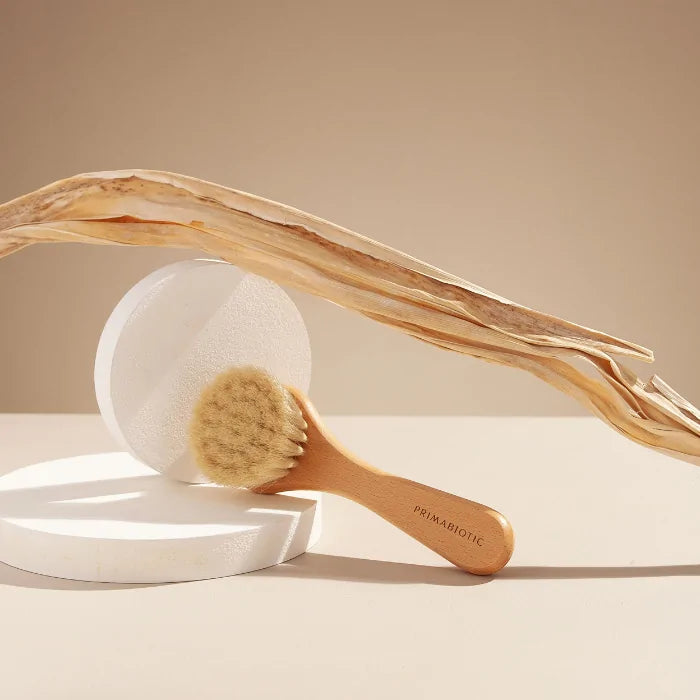 Primabiotic natural face massage brush with wooden handle and soft bristles, designed for gentle cleansing and glowing skin.