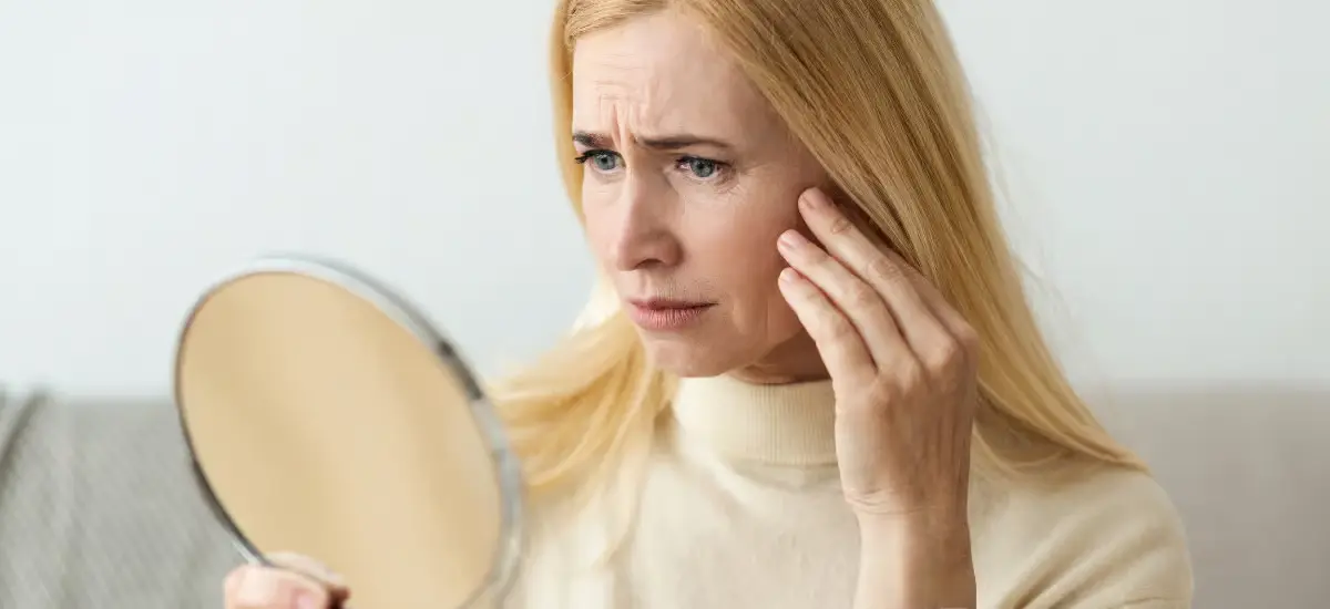 woman checks the wrinkles on her face in the mirror