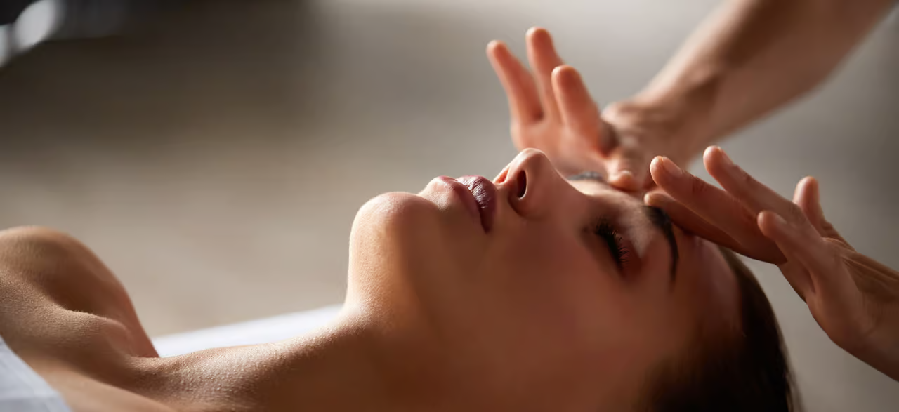 woman lying down and receiving a facial massage